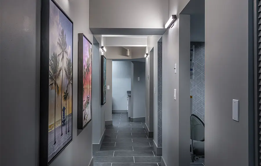 Modern medical office hallway with gray walls, artwork, and professional lighting leading to examination rooms