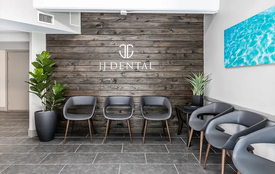 Modern dental office waiting room with gray chairs, wood accent wall, and JFDental logo - in Fort Lauderdale, FL