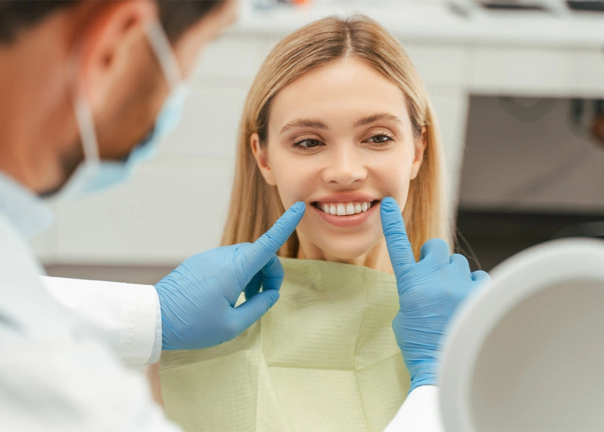 Dentist showing patient their smile using mirror during dental examination in modern clinic