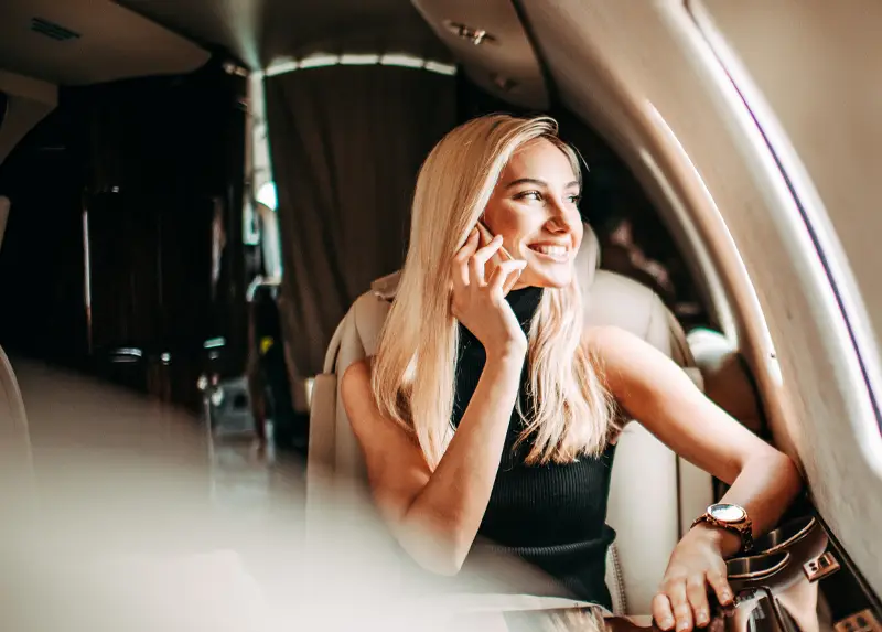 Woman talking on phone while sitting in private jet cabin with luxury interior