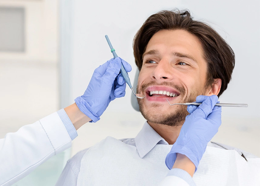 Dentist examining patient's teeth during dental checkup with mirror and explorer tools