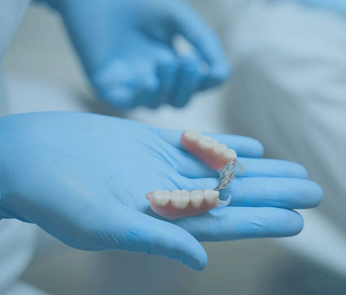 Dentist holding dental implant bridge in gloved hand showing tooth replacement option